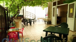 Летний внутренний дворик мини отеля в Сочи с мебелью под тенистым виноградником.