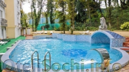 Открытый бассейн на территории отеля в Сочи «Империя» в окружении хвойного леса и яркого, жаркого солнца.